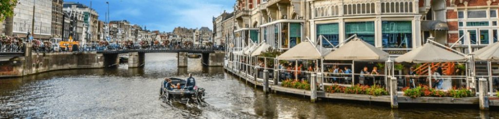 Boat trip in Amsterdam showing a boat on the water with a cafe at the side.